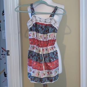A colorful romper with some cream lace detailing